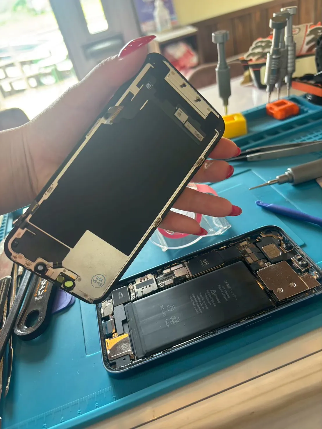 女性スタッフがiPhoneの内部を開けて修理する様子
