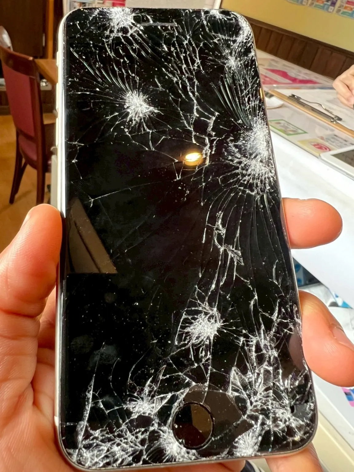 粉々に割れた画面を手に持っているiPhoneの画面交換相談